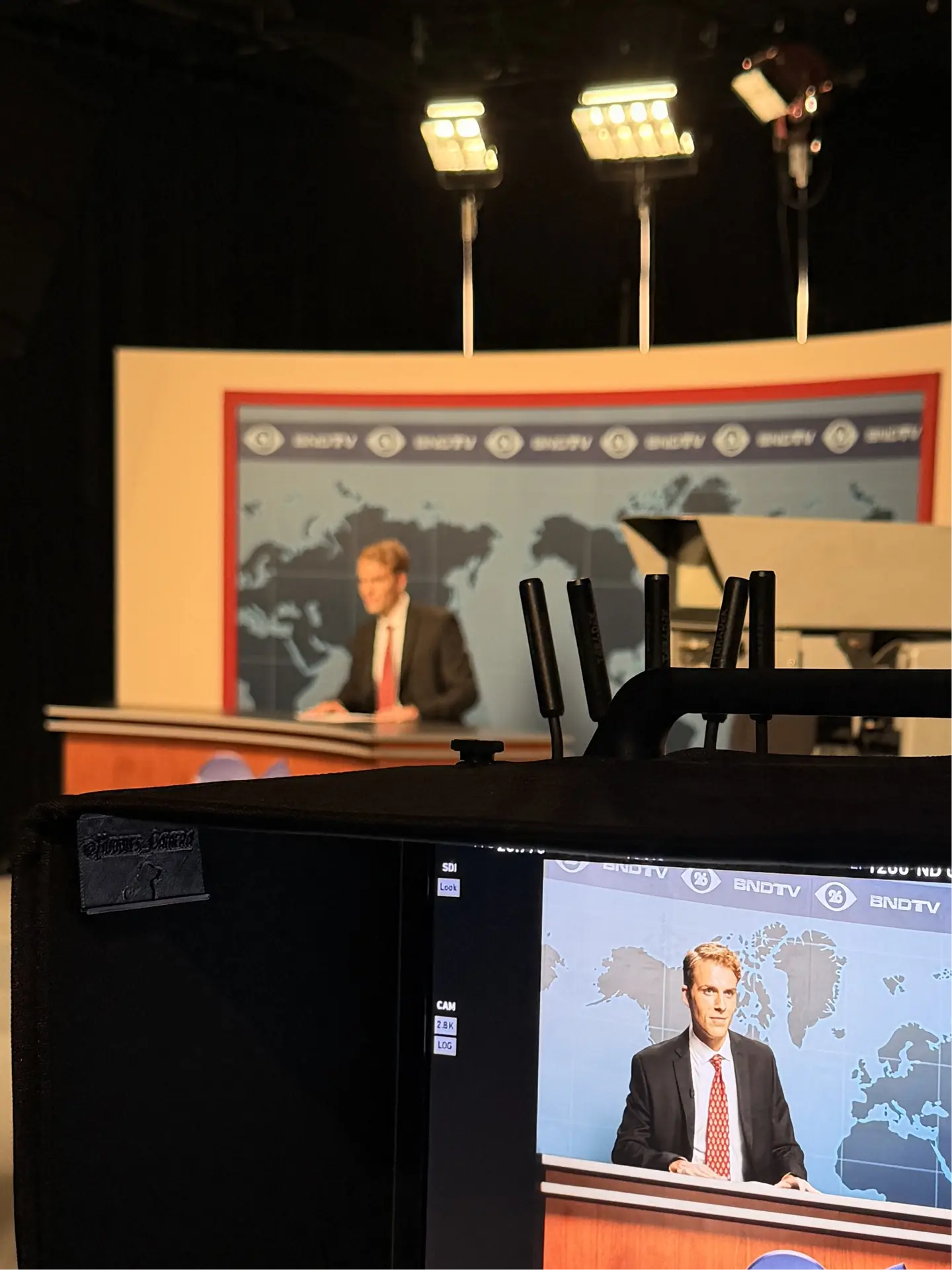 Anchor at the news desk seen through the monitor